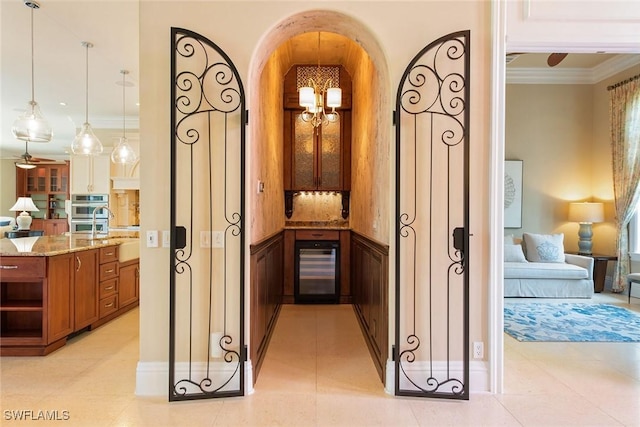 hallway featuring light tile patterned floors, crown molding, a notable chandelier, and beverage cooler