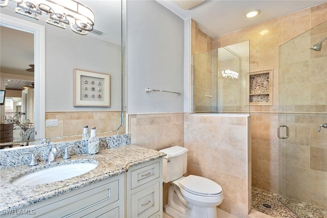 bathroom featuring vanity, toilet, tile walls, and walk in shower