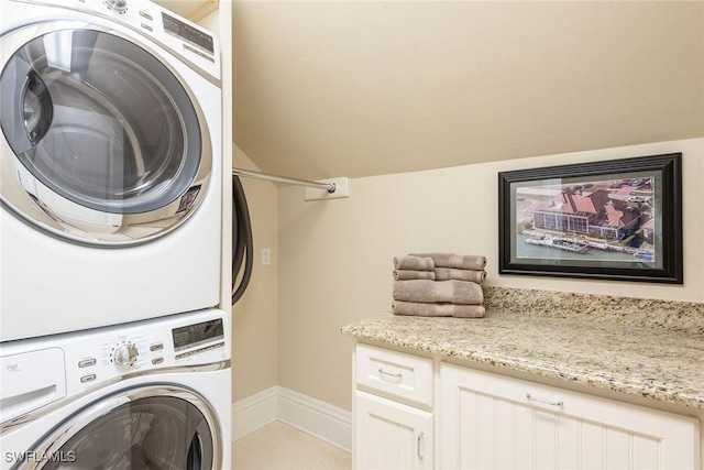 clothes washing area with cabinets and stacked washer and clothes dryer