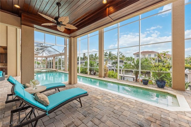 view of pool with ceiling fan, glass enclosure, and a patio area