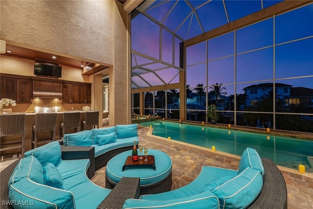 pool at dusk featuring a lanai, an outdoor hangout area, and a patio