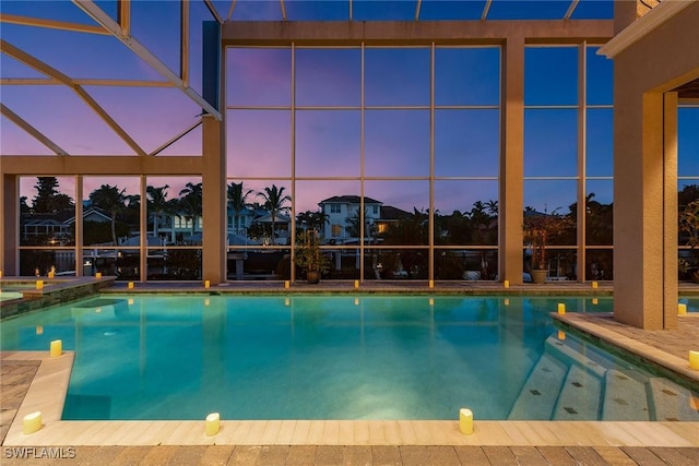 pool at dusk featuring glass enclosure