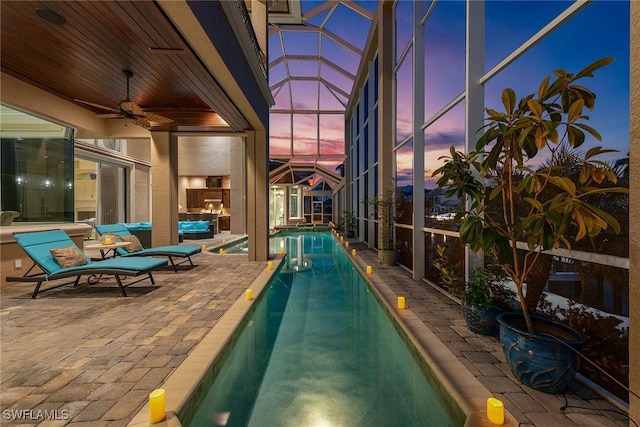 pool at dusk with an outdoor living space, a lanai, a patio area, and ceiling fan