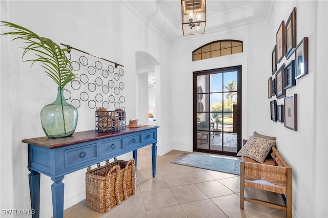 foyer with light tile patterned floors, crown molding, and a towering ceiling