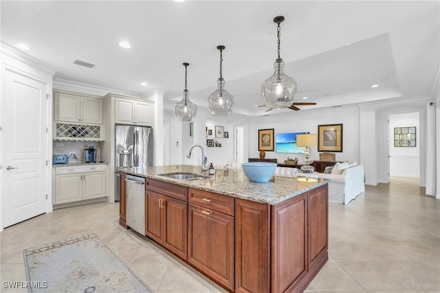 kitchen with stainless steel appliances, a kitchen island with sink, sink, and decorative light fixtures