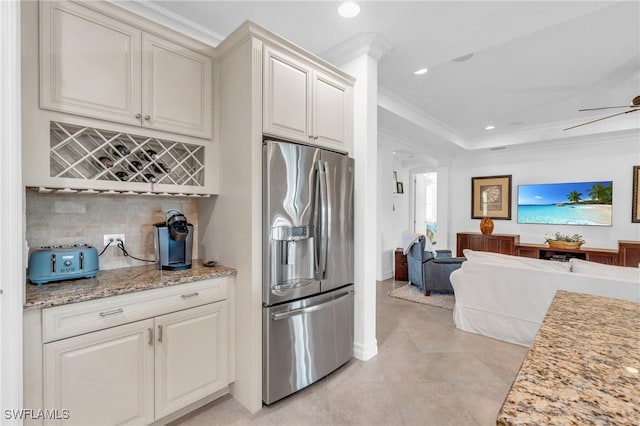 kitchen featuring stainless steel fridge, ceiling fan, tasteful backsplash, light stone countertops, and ornamental molding