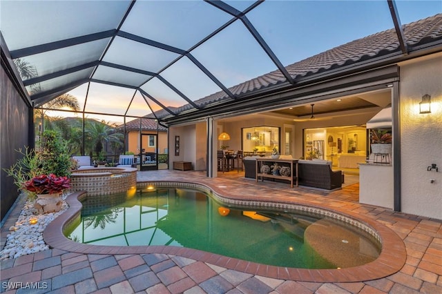 pool at dusk featuring an in ground hot tub, an outdoor hangout area, a patio area, and a lanai