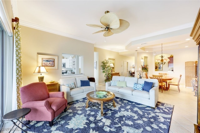 tiled living room with a raised ceiling, crown molding, and ceiling fan with notable chandelier