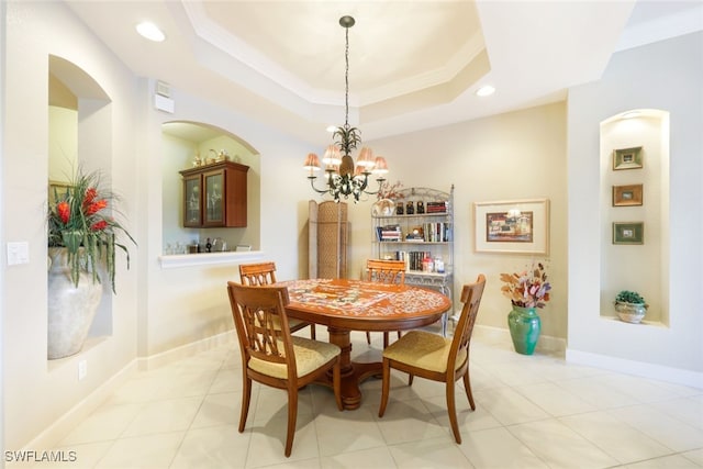 tiled dining area with crown molding, a tray ceiling, and a chandelier