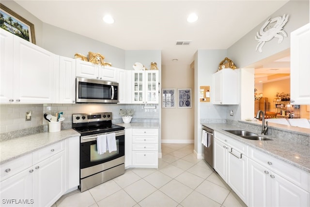 kitchen with appliances with stainless steel finishes, sink, decorative backsplash, and white cabinets