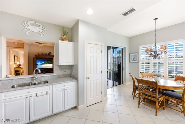 kitchen featuring sink, white cabinets, hanging light fixtures, light tile patterned floors, and light stone countertops