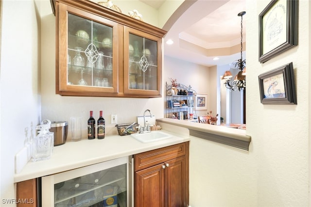 bar with pendant lighting, sink, wine cooler, a tray ceiling, and crown molding