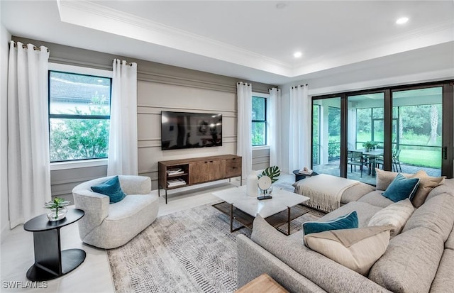 living room with crown molding, plenty of natural light, and a raised ceiling