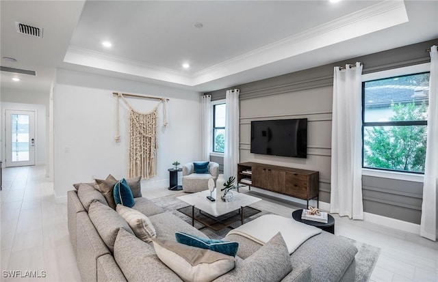 living room with a raised ceiling and crown molding