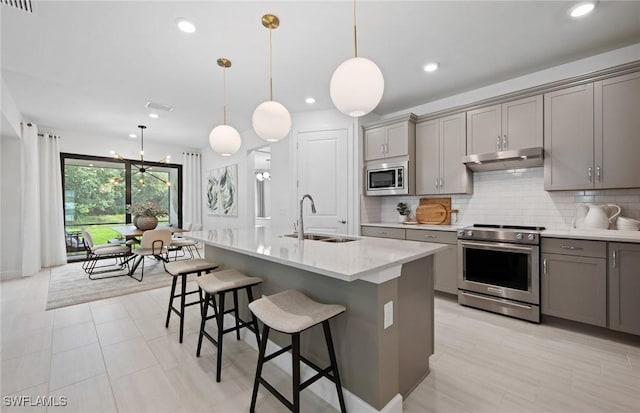 kitchen with sink, hanging light fixtures, a center island with sink, appliances with stainless steel finishes, and gray cabinets