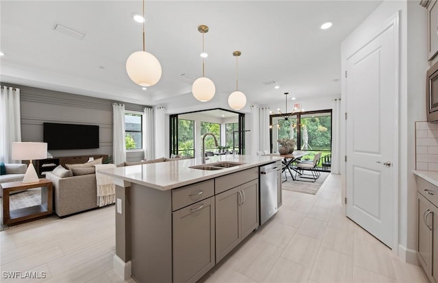 kitchen with pendant lighting, sink, stainless steel dishwasher, and a kitchen island with sink