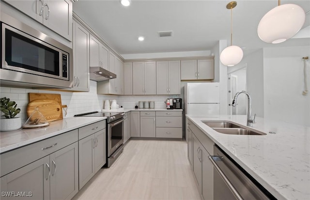 kitchen featuring sink, gray cabinetry, appliances with stainless steel finishes, pendant lighting, and exhaust hood