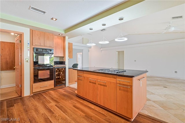 kitchen with pendant lighting, wine cooler, black double oven, a center island, and gas stovetop