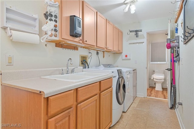 laundry area featuring cabinets, separate washer and dryer, and sink