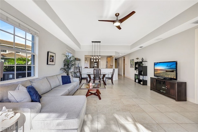 living room featuring light tile patterned floors, a tray ceiling, and ceiling fan