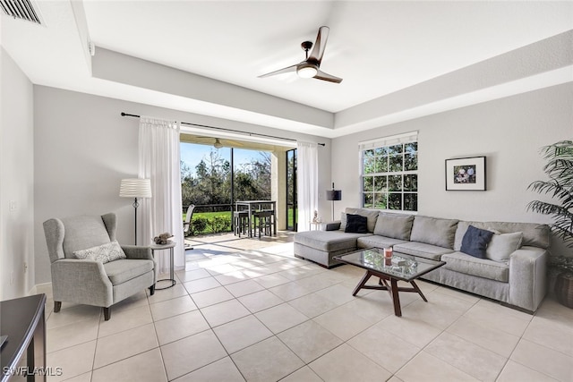 tiled living room featuring a tray ceiling and ceiling fan