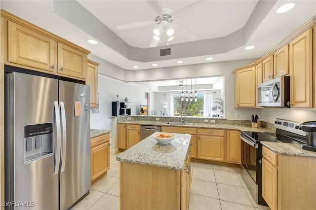 kitchen with stainless steel appliances, a raised ceiling, sink, and kitchen peninsula