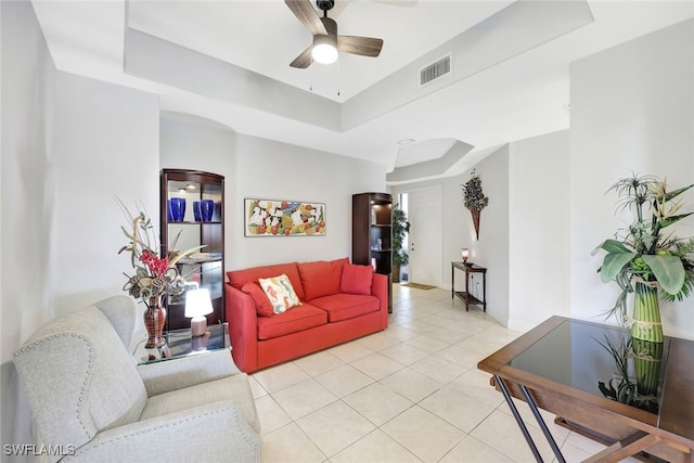 living area featuring visible vents, baseboards, ceiling fan, light tile patterned flooring, and a raised ceiling