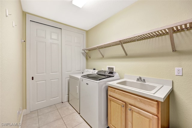 clothes washing area featuring a sink, cabinet space, light tile patterned floors, and washer and dryer