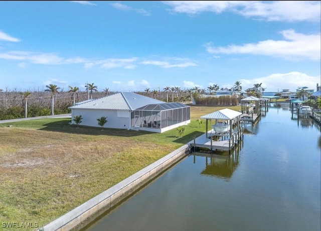 view of dock with a lanai, a water view, and a lawn