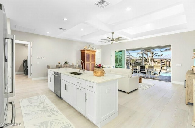 kitchen featuring coffered ceiling, sink, white cabinetry, a center island with sink, and light wood-type flooring