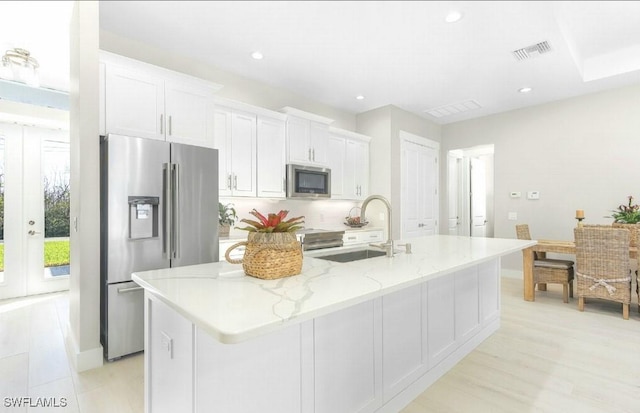 kitchen with sink, an island with sink, white cabinets, and appliances with stainless steel finishes