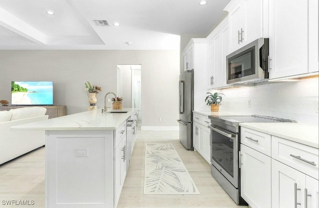 kitchen with sink, stainless steel appliances, an island with sink, and white cabinets