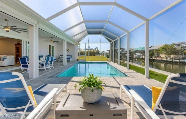 view of pool with a patio, a water view, ceiling fan, and glass enclosure