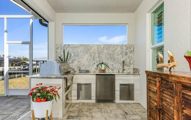 interior space featuring a water view, area for grilling, an outdoor kitchen, and sink