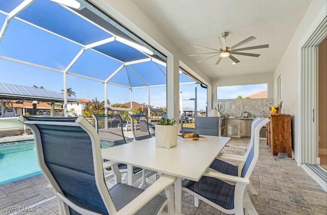 view of patio with exterior kitchen, a lanai, and ceiling fan