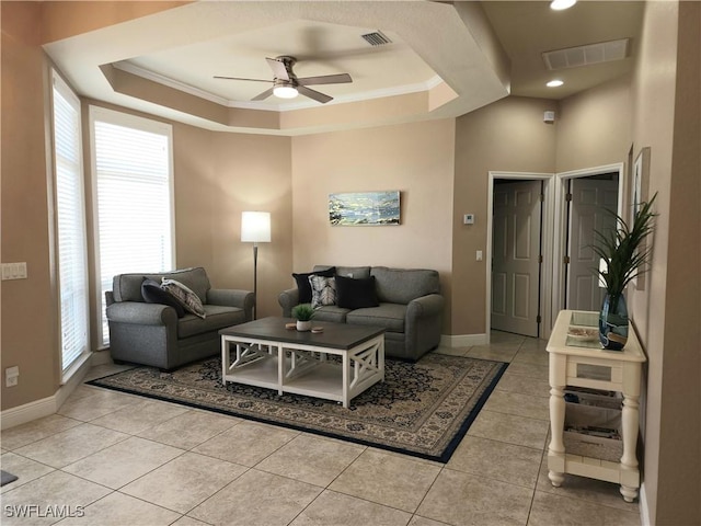 living room with a raised ceiling, ceiling fan, light tile patterned floors, and crown molding