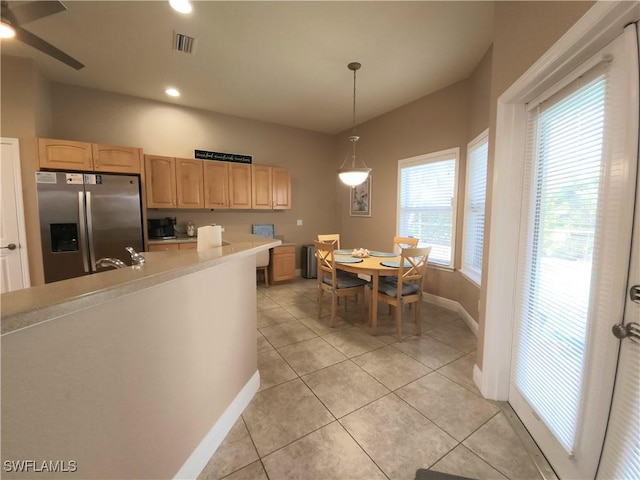 kitchen with light tile patterned floors, decorative light fixtures, stainless steel fridge with ice dispenser, and light brown cabinets