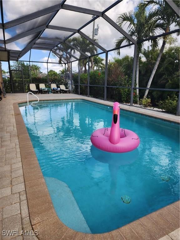 view of pool with a patio area and glass enclosure