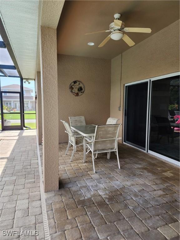 view of patio with ceiling fan and glass enclosure