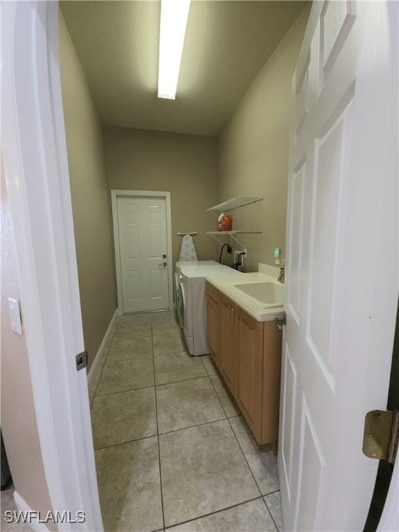 clothes washing area with separate washer and dryer, sink, light tile patterned floors, and cabinets