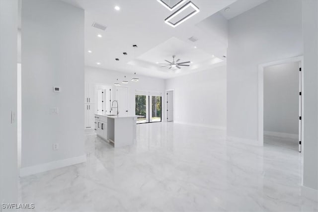 interior space with sink, a raised ceiling, and ceiling fan