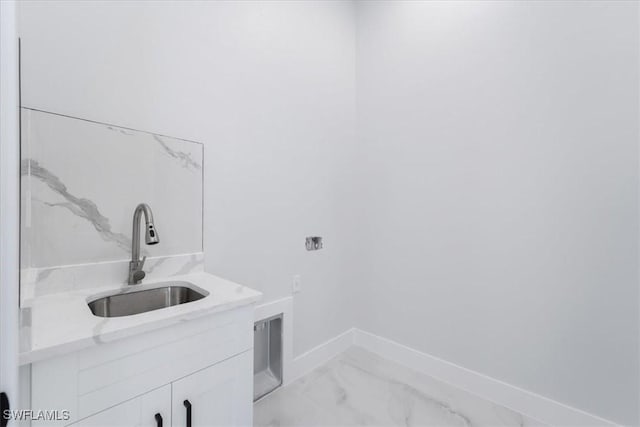 clothes washing area with cabinets and sink