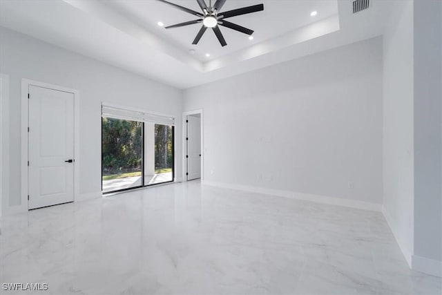 spare room featuring a raised ceiling and ceiling fan