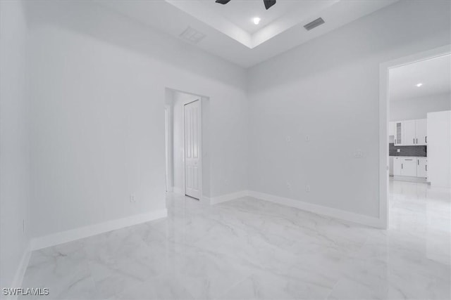 spare room with ceiling fan and a tray ceiling