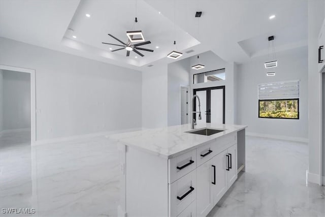 bathroom with sink, ceiling fan, a high ceiling, a tray ceiling, and french doors