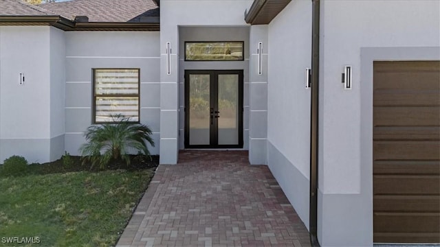 view of exterior entry featuring a garage and french doors