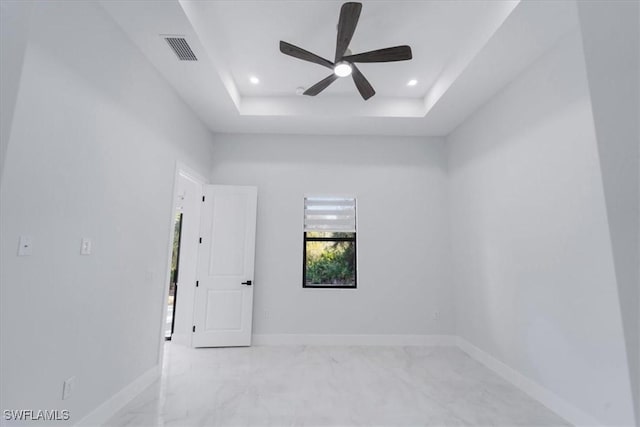 unfurnished room with ceiling fan and a tray ceiling