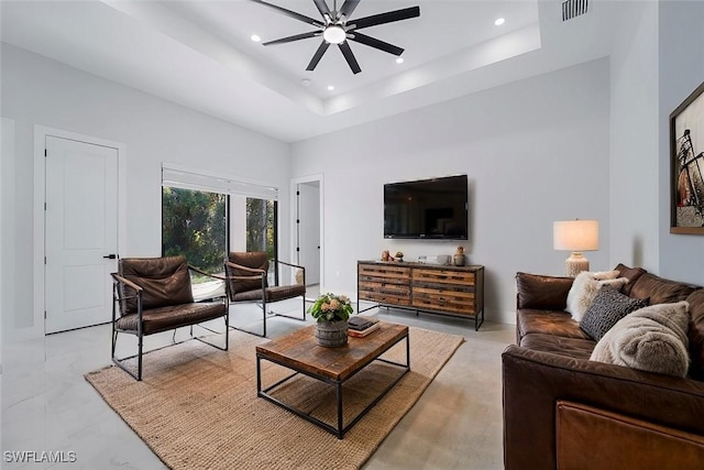 living room with a high ceiling, ceiling fan, and a tray ceiling