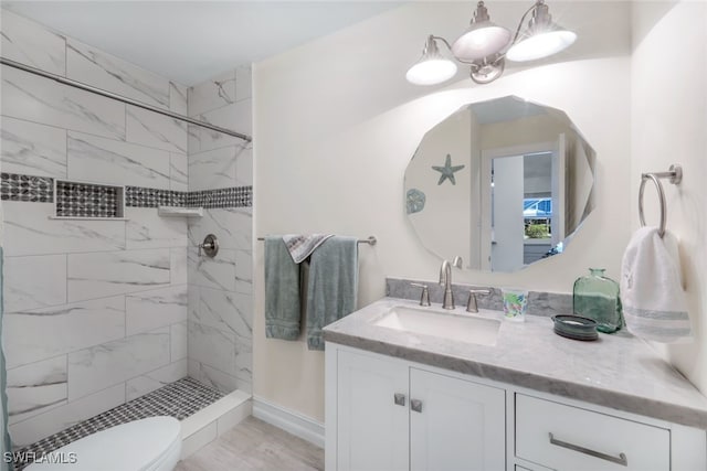 bathroom featuring a tile shower, vanity, and toilet