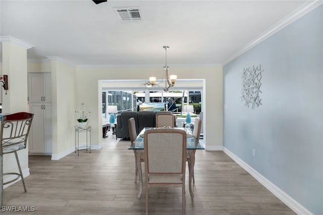 dining space featuring ornamental molding, a chandelier, and light wood-type flooring